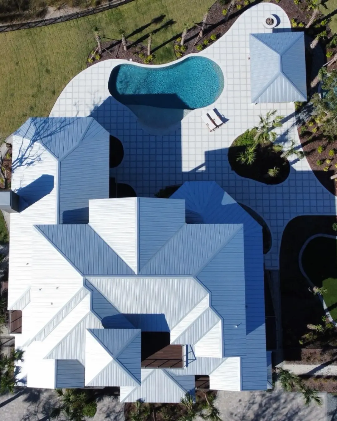an aerial shot of a completed roof, a pool and greenery